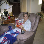 Eva sitting in her recliner doing two of her favorite things: reading and being warmed by one of her own knitted afghans.